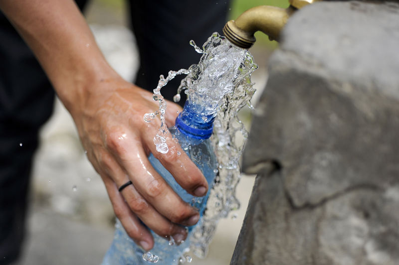 Person filling a bottle of water from a tap